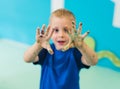 Nursery school. Cute blonde toddler boy showing his painted colorful palms. Art class with finger painting for kids Royalty Free Stock Photo