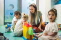 Nursery school. Toddlers and their teacher playing with colorful plastic playhouses, cars and boats. Imagination