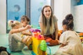 Nursery school. Toddlers and their teacher playing with colorful plastic playhouses, cars and boats. Imagination