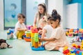 Nursery school. Toddlers and their teacher playing with colorful plastic playhouses, cars and boats. Imagination