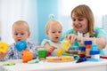 Nursery teacher looking after children in daycare. Little kids toddlers play together with developmental toys. Royalty Free Stock Photo