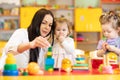 Nursery teacher looking after children in daycare. Little kids toddlers play together with developmental toys. Royalty Free Stock Photo