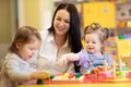 Nursery teacher looking after children in daycare. Little kids toddlers play together with developmental toys. Royalty Free Stock Photo