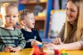 Nursery teacher looking after children in daycare. Little kids toddlers play together with developmental toys. Royalty Free Stock Photo