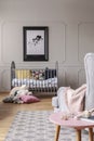 Nursery with wooden crib with cushions, real photo with mockup on the grey wall