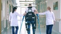 Nurses are helping a handicapped patient to walk in the exosuit
