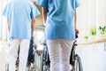 Nurses pushing seniors in wheelchair thru nursing home Royalty Free Stock Photo