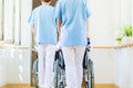 Nurses pushing seniors in wheelchair thru nursing home Royalty Free Stock Photo