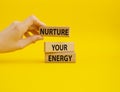 Nurture your Energy symbol. Concept words Nurture your Energy on wooden blocks. Businessman hand. Beautiful yellow background.