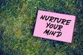 Nurture your mind quote written on paper on green grass background. The effect of thoughts on mind and body concept