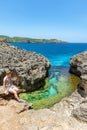 Unidentified woman sitting at the edge of cliff at Angel`s Billabong Royalty Free Stock Photo