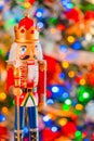 A nutcracker king with a  jeweled crown and scepter stands in front of  a  soft focused decorated Christmas tree Royalty Free Stock Photo