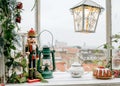 Nutcracker ornament, a cake, and a lantern on a wooden table facing the city