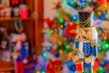 A nutcracker plays a drum in front of Christmas tree and armoire Royalty Free Stock Photo