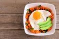 Nutrient bowl with sweet potato, egg, avocado and spinach over rustic wood