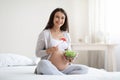 Happy pregnant young woman eating fresh salad at home Royalty Free Stock Photo