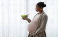 Happy pregnant young black woman eating vegetable salad at home Royalty Free Stock Photo