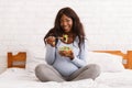 Happy pregnant woman eating fresh salad on bed at home Royalty Free Stock Photo