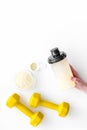 Nutrition for muscle growth. Scoop of protein near shaker and dumbbell on white background top view copy space Royalty Free Stock Photo