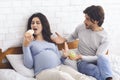 Hungry pregnant woman eating croissant instead of green apple Royalty Free Stock Photo