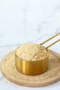 Nutritional yeast flakes in a measuring cup on white kitchen table Royalty Free Stock Photo
