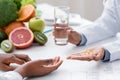 Nutritionist giving pills and glass of water to female patient Royalty Free Stock Photo