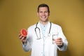 Nutritionist holding glass of pure water and grapefruit on yellow background