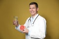 Nutritionist holding glass of pure water and ripe grapefruit on background