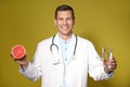 Nutritionist holding glass of pure water and ripe grapefruit on background