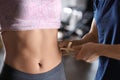 Nutritionist measuring woman`s body fat layer with caliper, closeup