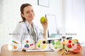 Nutritionist`s recommendations. Doctor with apple and clipboard at desk