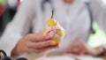 Nutritionist showing ripe yellow pear with measuring tape while sitting in medical office. Royalty Free Stock Photo