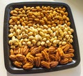 Nuts almonds, pistachios and pecans on black plate, close-up, set.