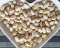 Nuts arranged in heart on background. Healthy Food image close up pistachios on the cup plate. Love Texture on top view mock up