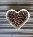 Nuts arranged in heart shape on background. Food image close up candy, chocolate milk, extra dark almond nuts. Love Texture