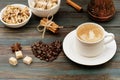 Nuts in bowl, coffeepot, heart-shaped coffee beans, cinnamon, anise, sugar, and cap of coffee on wooden background Royalty Free Stock Photo