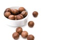 Nuts of Macadamia Integrifolia L, also known as Macadamia nuts, in white bowl and scattered around on white background