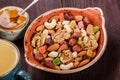 Nuts mix in a bowl, cup of tea and honey on dark wooden background close up. Walnuts, pistachios