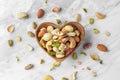 Nuts mixed in heart wooden bowl on marble table Royalty Free Stock Photo