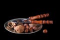 Nuts with nutcrackers on plate, black background.