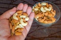 Nuts in palm hand nuts in bowl brown table cashews almonds raisins