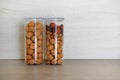 Nuts, walnuts and hazelnut, and dry red berries in large glass jars containers stand on gray table in kitchen. Vegetarian healthy Royalty Free Stock Photo