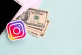 Instagram paper logo lies with envelope full of dollar bills and smartphone