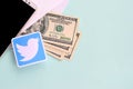 Twitter paper logo lies with envelope full of dollar bills and smartphone