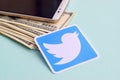 Twitter paper logo lies with envelope full of dollar bills and smartphone