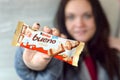 Young woman shows Kinder Bueno white Chocolate Candy Bar in colored wrapping. Kinder Bueno by Italian Confectionery Manufacturer