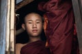 Nyaungshwe, Myanmar - April 2019: portrait of a young novice Buddhist monk looking out of the window Royalty Free Stock Photo