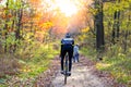 Young athletic man cyclist riding bike on the trail in sunny forest. Back view. Healthy lifestyle and travel concept.