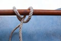 Nylon ship ropes tied knot around a round piece of wood on cement flooring closeup.