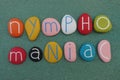 Nymphomania word composed with multi colored stones over green sand